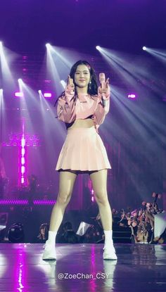 a woman standing on top of a stage with her hands up in front of her