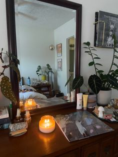 a mirror sitting on top of a wooden dresser next to a table filled with candles