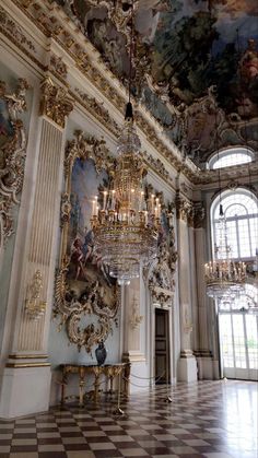 an ornate room with chandelier and paintings on the walls