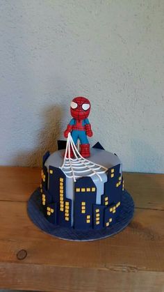 a spiderman cake on a wooden table with a white wall in the back ground