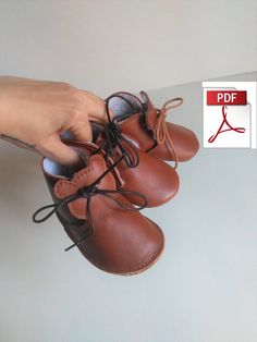 a person is holding two brown shoes with laces on the bottom and one in the middle