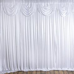 an empty room with white curtains and wooden floors