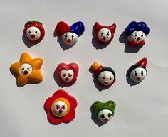 several clown faces are placed in the shape of hearts and star buttons on a white surface