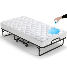 a person is pouring blue liquid on a mattress that's attached to a bed frame