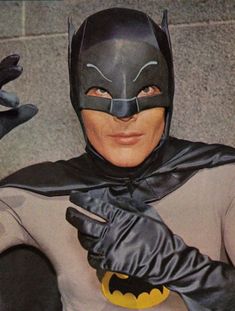 a man dressed as batman pointing to the left with his right hand in front of him