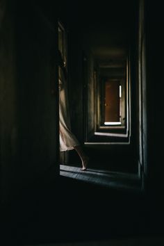 a person standing in an open doorway with their hand on the door handle and light coming through