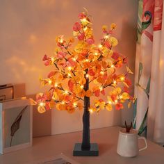 a lighted tree on a table next to a cup