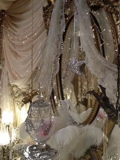 an elaborate mirror and chandelier in a room with white drapes hanging from the ceiling