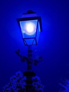 a street lamp lit up in the dark with blue light shining on it's side