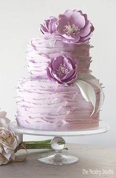 a three tiered cake with purple flowers on top