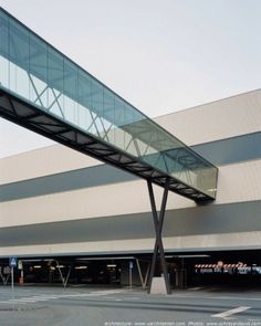 an empty parking lot next to a large building with a glass walkway over the entrance