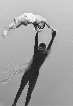 a man holding a baby in the air above water