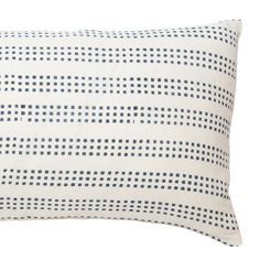 a white and blue pillow with black dots on the front, sitting against a white background