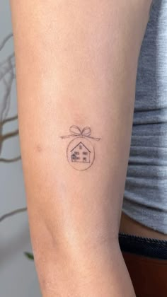 a woman's arm with a small house tattoo on the back of her left arm