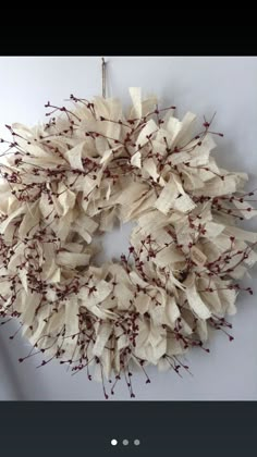 a white wreath with red berries hanging on the wall