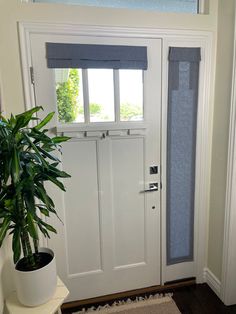 a white front door with a potted plant next to it and blinds on the side