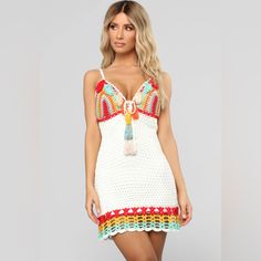 a woman wearing a white crochet dress with colorful tassels