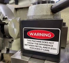 a warning sign on the side of a machine that is turning it's gears