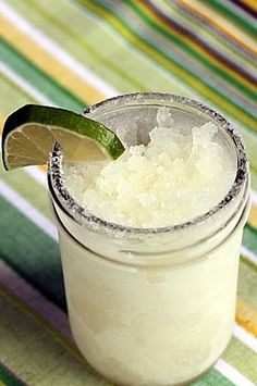 a small glass filled with white liquid and a lime wedge on the rim next to it