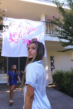 a woman standing in front of a building with a banner hanging from it's side