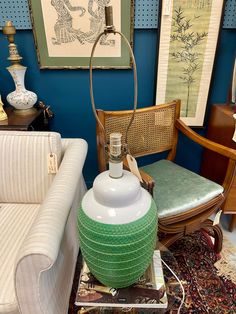 a green lamp sitting on top of a table next to a white chair and couch