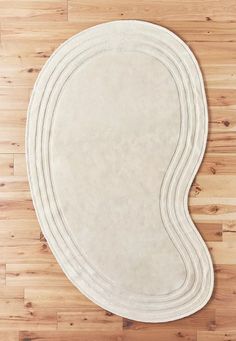 a white rug on top of a wooden floor with an oval shaped design in the middle