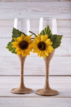 two wine glasses decorated with sunflowers on top of burlied glassware