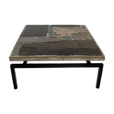 a coffee table made out of stone with black metal legs and a square shaped top