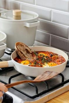 a pan filled with food sitting on top of a stove next to other pots and pans