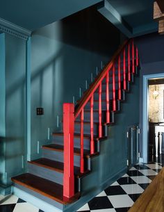 a staircase with red railing and black and white checkered flooring in a house