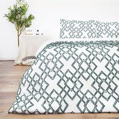 a white and black bed with two pillows on top of it next to a potted plant