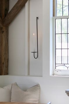 a candle is lit in the corner of a room with white walls and wood beams