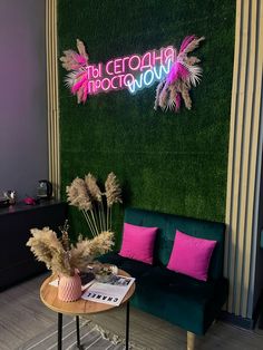 a living room with green grass and pink pillows on the couch, next to a neon sign