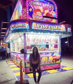 a woman standing in front of a candy machine at an amusement park with lights on