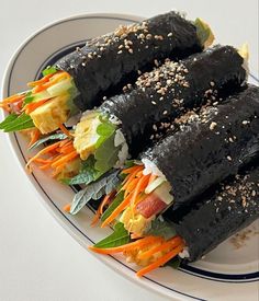 three rolls on a plate with vegetables and sesame seeds