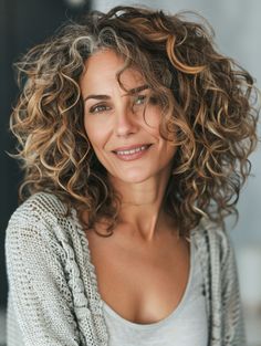 Enhance your natural curls by adding highlights that create dimension and depth. This style is perfect for showcasing the beauty of your natural hair texture while brightening your overall look. It works well on all hair lengths and is particularly flattering for darker skin tones. Gray Highlights On Curly Hair, Mid Length Curly Hair Highlights, Loose Perm Short Hair, Enhancing Gray Hair, Curly Hairstyle Ideas, Grey Hair Transformation, Natural Curly Hair Cuts, Grey Curly Hair, Highlights Curly Hair