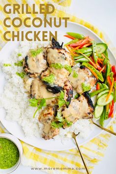 a white plate topped with chicken covered in gravy next to rice and veggies