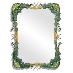 a decorative mirror with green leaves and vines on the frame, hanging on a wall