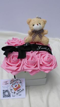 a teddy bear sitting on top of pink roses