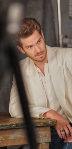 a man sitting at a wooden table with his hand on his chin and looking off to the side