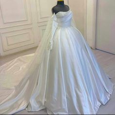 a white wedding dress on display in a room with an open door and mannequin