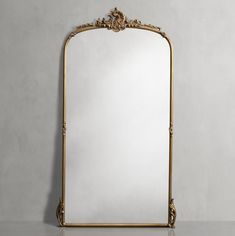 an ornate gold framed mirror against a gray wall