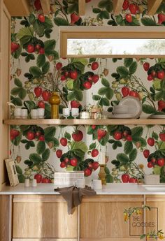 a kitchen with apples on the wall and green leaves on the wall behind the shelves