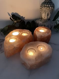 three lit candles sitting next to a buddha statue