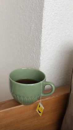 a cup of coffee sitting on top of a wooden shelf