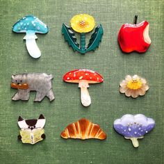 there are many different types of brooches on the green tablecloth with flowers and animals