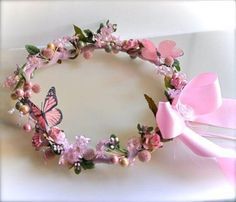 a pink flower crown with butterflies and pearls