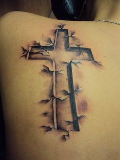 a cross tattoo on the back of a woman's shoulder