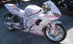 a pink and white motorcycle parked in a parking lot