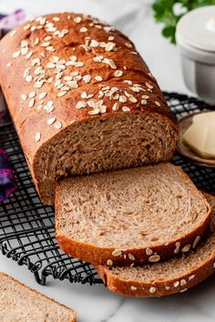 a loaf of bread sitting on top of a cooling rack next to some sliced bread